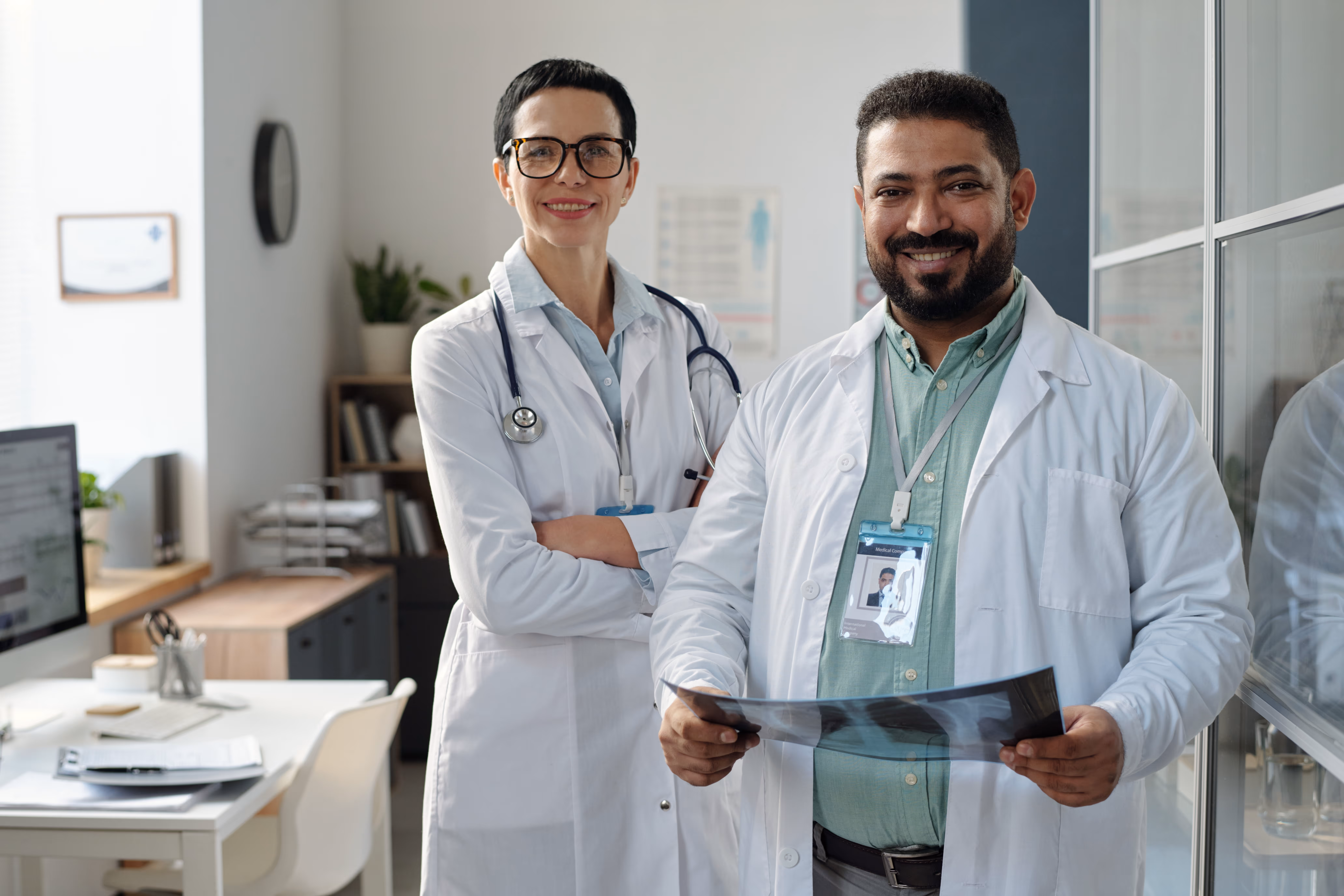 Two doctors standing together smile looking at the camera